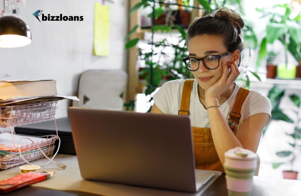 Young female business owner in glasses using laptop looking for the best small business loans online