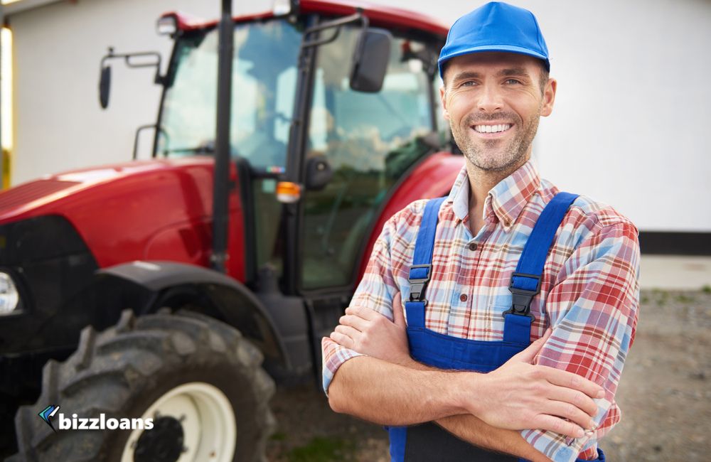 smiling business owner in front of heavy equipment